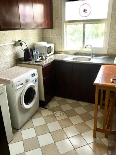 a kitchen with a washing machine and a sink at Lotus Furnished Hotel Apartments LLC. Ajman in Ajman 