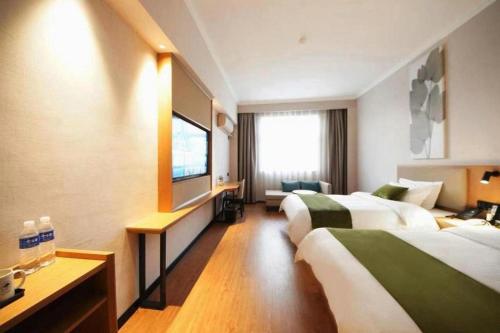a hotel room with two beds and a flat screen tv at GreenTree Inn Luoyang Henan University of Science and Technology in Luoyang