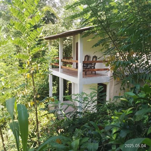 a building with two chairs in the middle of a forest at Kit Cott Resort and Retreat in Teligama