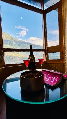 a table with two glasses and a bottle of wine at Ocean Dreams & Hotel Meadows Dream ! Bikers,Couple & Family Hotel ! Valley View ! Open Terrace Cafe in Manāli