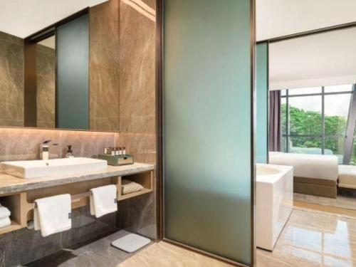 AMIGO migo Sleeping Hotel (mission hills) في Tiantangwei: حمام مع حوض استحمام ومغسلة ومرآة