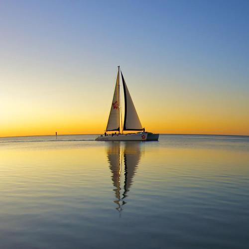 a sail boat in the water at sunset at Wildsights Beach Units in Denham