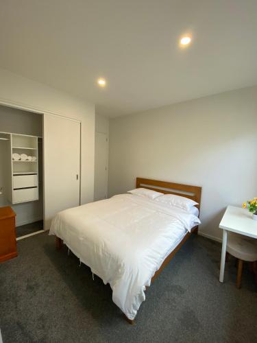 a bedroom with a large white bed and a desk at CozyNest3 -Private entrance and bath in Auckland