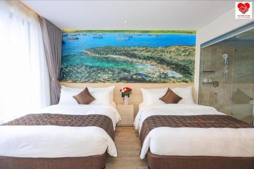 two beds in a room with a painting on the wall at Victor Group - Sam Sam Phu Yen Condotel in Phước Hậu