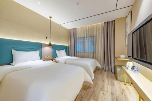 a hotel room with three beds and a flat screen tv at ZMAX Hotels Shenzhen Lianhuacun Metro Station in Shenzhen