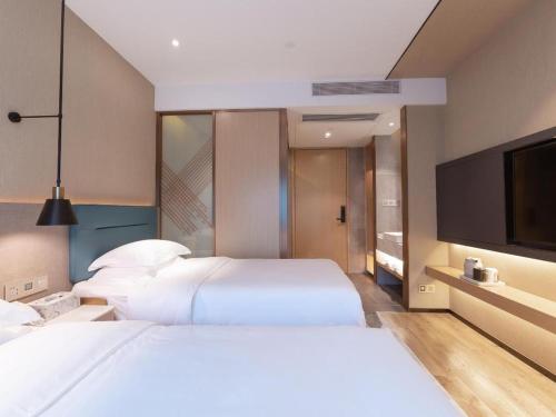 a bedroom with two beds and a flat screen tv at ZMAX Hotels Shenzhen Lianhuacun Metro Station in Shenzhen