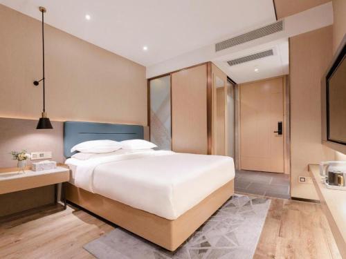 a bedroom with a large white bed and a bathroom at ZMAX Hotels Shenzhen Lianhuacun Metro Station in Shenzhen