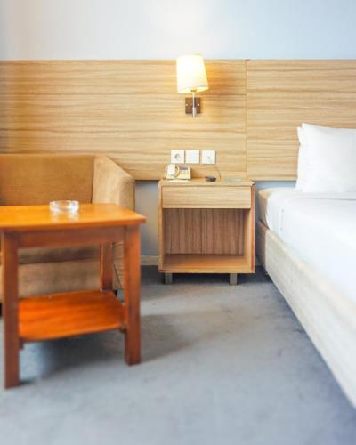 a bedroom with a bed and a desk and a bed and a table at Hotel Dafam Pekanbaru in Pekanbaru