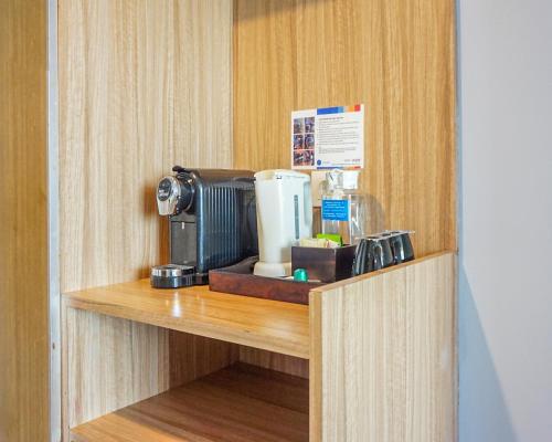 a coffee maker on a shelf in a room at Hotel Dafam Pekanbaru in Pekanbaru