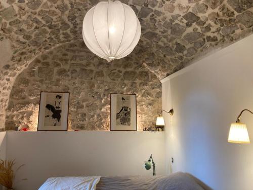 PeilleにあるBastide Peille village panoramic view and gardenの石壁のベッドルーム(ベッド1台、ランプ付)