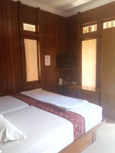 two beds in a room with wooden walls and windows at HENDRO'S SURF CAMP Pulau merah in Pasanggaran