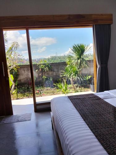 a bedroom with a bed and a large window at MMMpulukansurfvilla in Medewi