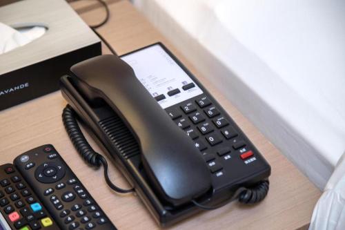 a desk with a phone next to a remote control at Lavande Hotel Guangzhou Quzhuang Metro Station in Guangzhou