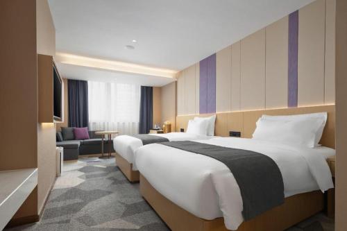 a hotel room with two beds and a couch at Lavande Hotel Guangzhou Quzhuang Metro Station in Guangzhou