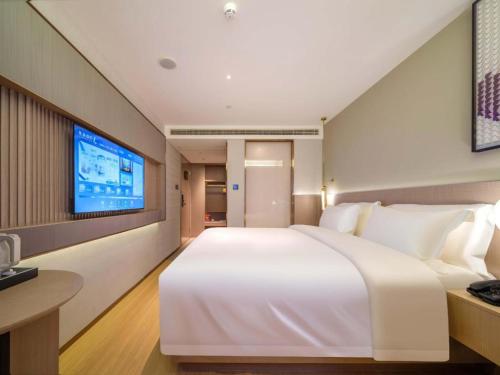 a bedroom with a large white bed and a tv at Lavande Hotel Guangzhou Quzhuang Metro Station in Guangzhou