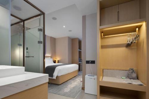 a bathroom with a bedroom with a bed and a sink at Lavande Hotel Guangzhou Quzhuang Metro Station in Guangzhou