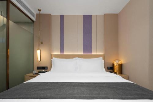 a bedroom with a large bed and a striped wall at Lavande Hotel Guangzhou Quzhuang Metro Station in Guangzhou
