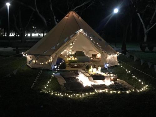 a tent with lights on the grass at night at Glamping kaki singapore-Standard medium bell tent in Singapore
