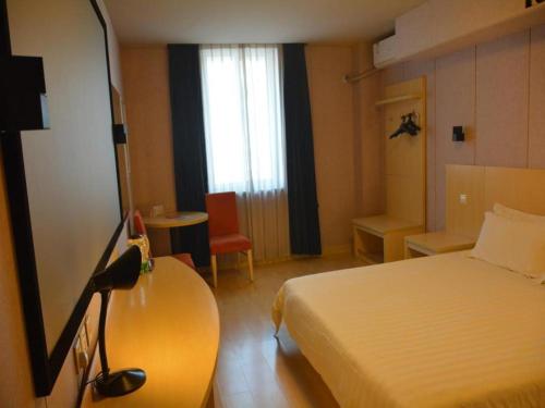 a hotel room with a bed and a table and a window at Jinjiang Inn Shenyang Northeastern University in Shenyang