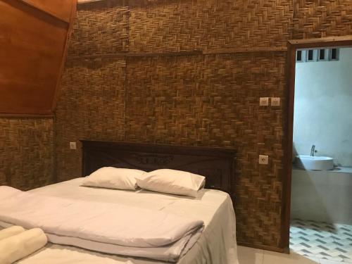 a bedroom with a bed with a brick wall at Bello Bungalow in Batukliang