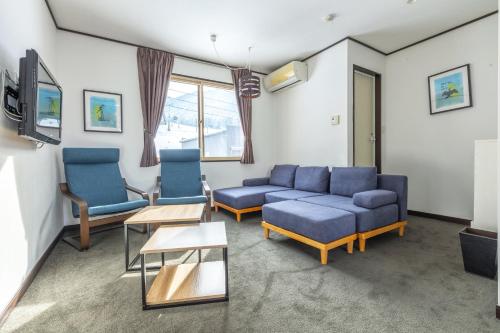 a living room with a couch and chairs and a tv at Address Nagasaka in Nozawa Onsen