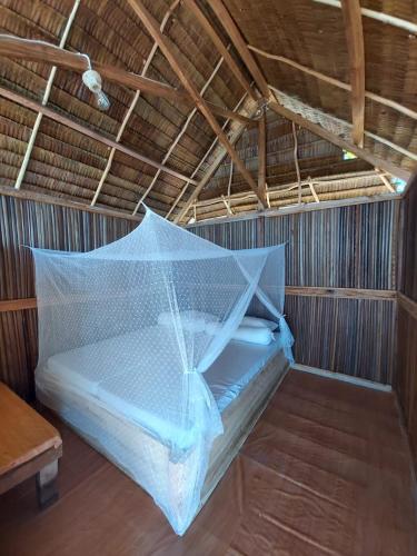a bed in a room with a mosquito net at Kasumasa Homestay in Fambemuk