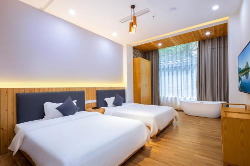 two beds in a hotel room with a bath tub at Qingshan Yuandai Boutique Homestay Yangshuo in Yangshuo