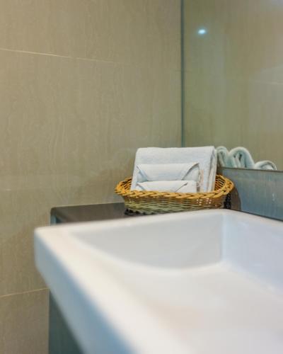 a basket of towels sitting on a counter in a bathroom at Hotel Dafam Pekanbaru in Pekanbaru