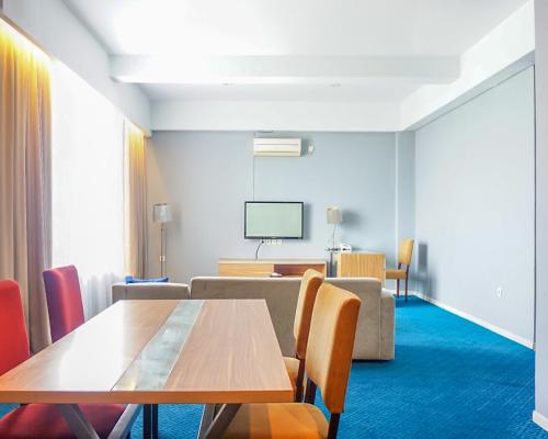 a room with a table and chairs and a tv at Hotel Dafam Pekanbaru in Pekanbaru