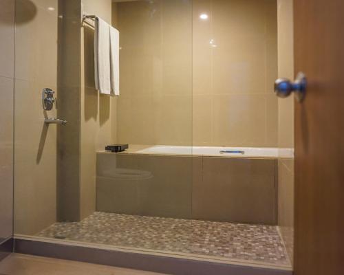 a bathroom with a shower with a glass door at Hotel Dafam Pekanbaru in Pekanbaru