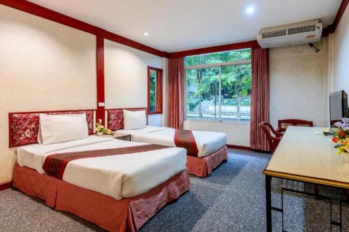 a hotel room with two beds and a window at Beverly Hill Park Hotel in Ban Pak Nam Pho