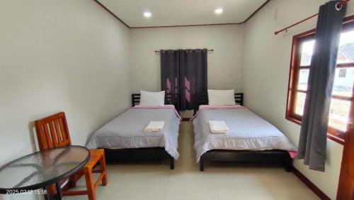 two beds in a room with a table and a window at Suanlamyai Resort in Loei