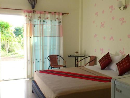 a bedroom with a bed and a window and a table at Suanlamyai Resort in Loei