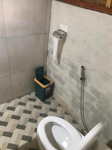 a bathroom with a toilet and a trash can at Bello Bungalow in Batukliang