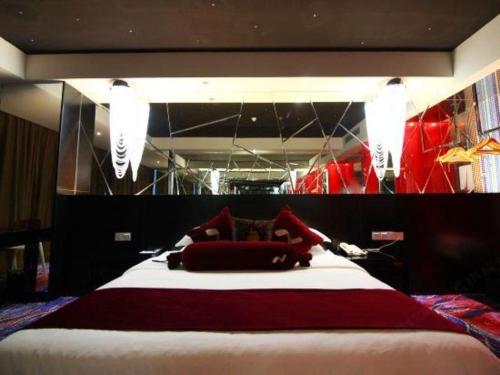 a bedroom with a large bed with red and white sheets at Grand Nest Hotel (Tang Jia Wan Beach) in Zhuhai