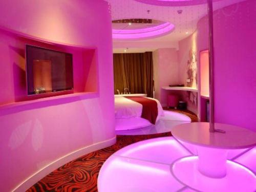 a pink room with a bed and a table at Grand Nest Hotel (Tang Jia Wan Beach) in Zhuhai