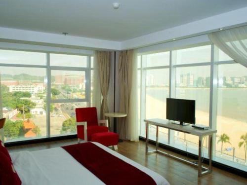 a hotel room with a bed and a tv and windows at Grand Nest Hotel (Tang Jia Wan Beach) in Zhuhai