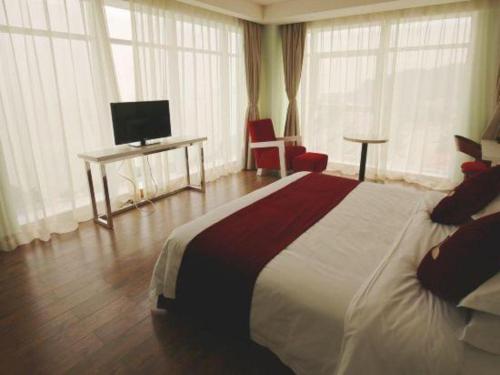 a hotel room with a large bed and a television at Grand Nest Hotel (Tang Jia Wan Beach) in Zhuhai
