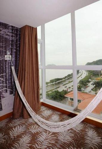 a hammock in a room with a large window at Grand Nest Hotel (Tang Jia Wan Beach) in Zhuhai