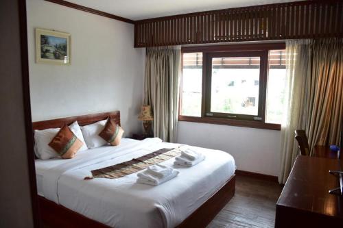 a bedroom with a large bed with a window at Hungheuang Hotel in Savannakhet