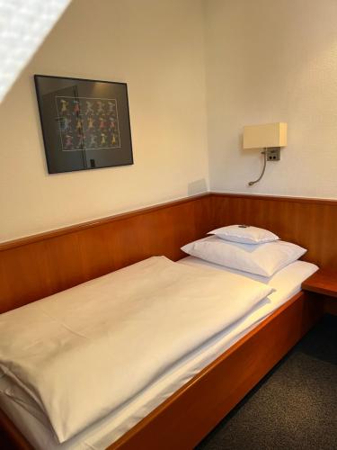 a bed in a small room with a picture on the wall at Historik Hotel Garni Christinenhof in Hameln