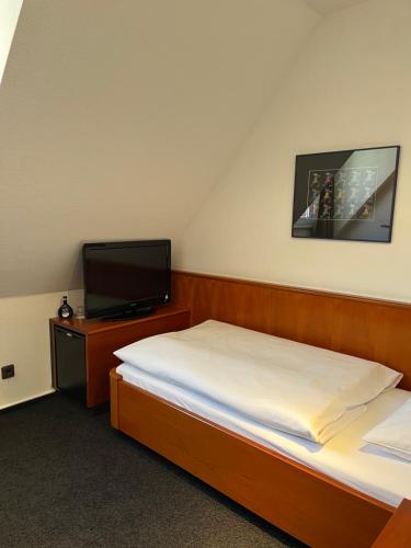 a bedroom with two beds and a flat screen tv at Historik Hotel Garni Christinenhof in Hameln