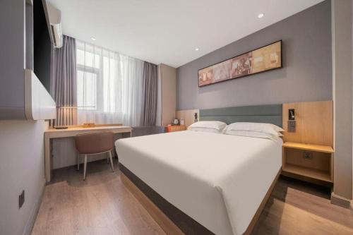 a bedroom with a large white bed and a desk at Jinjiang Inn Quanzhou West Street Kaiyuan Temple in Quanzhou