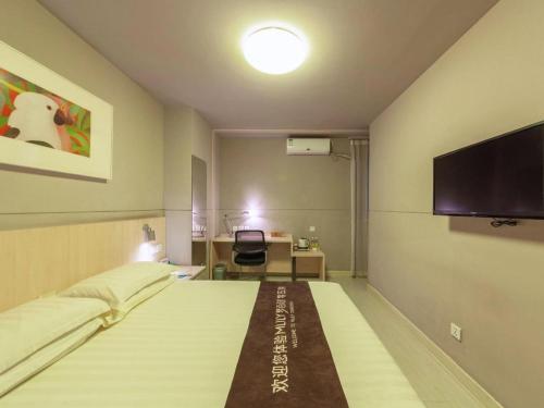 a hotel room with a bed and a flat screen tv at Jinjiang Inn Quanzhou West Street Kaiyuan Temple in Quanzhou