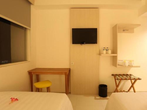 a bedroom with a bed and a television on the wall at Fovere Hotel Palangkaraya in Palangkaraya