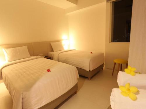 a hotel room with two beds and a window at Fovere Hotel Palangkaraya in Palangkaraya