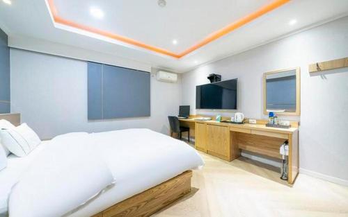 a bedroom with a bed and a desk and a television at Hotel Primo Daejeon in Daejeon