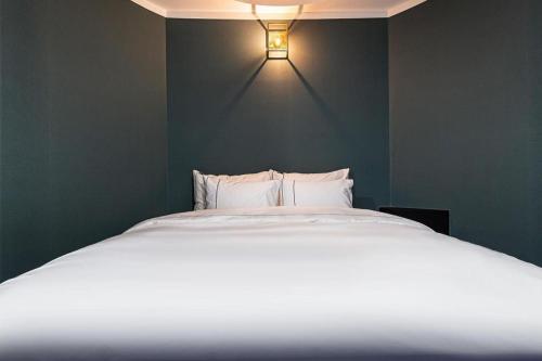 a bedroom with a white bed with a light on the wall at Hotel Primo Daejeon in Daejeon