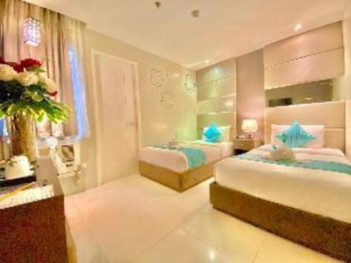 a bedroom with two beds and a window at Hotel Estrella in Tacloban