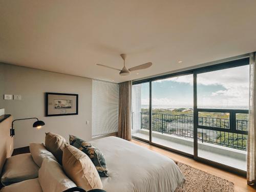1 dormitorio con cama, sofá y ventana grande en Sonvanger Villa Oceanfront Luxury, en Struisbaai